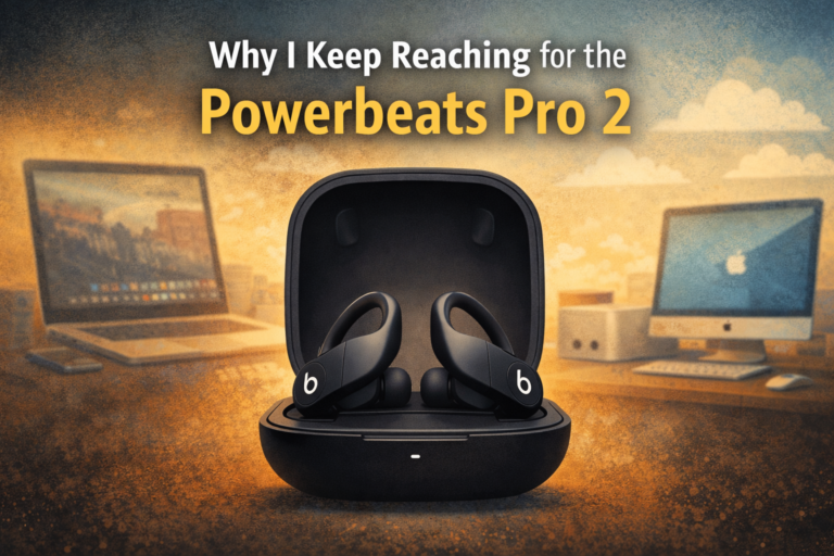 Powerbeats Pro 2 wireless earbuds in charging case on a desk with Apple computer setup in the background